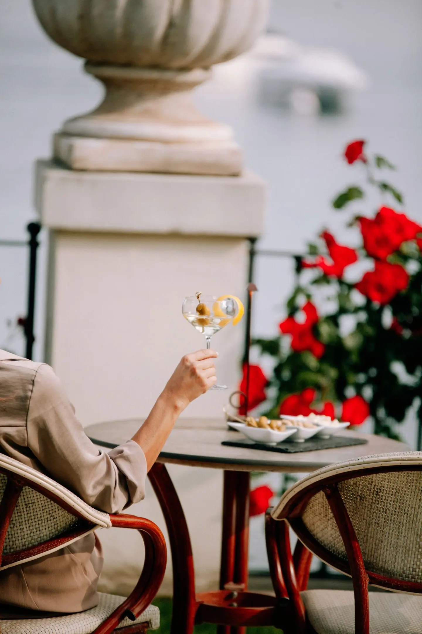 Un aperitivo al tavolino fra le rose rosse del giardino, con il lago sullo sfondo