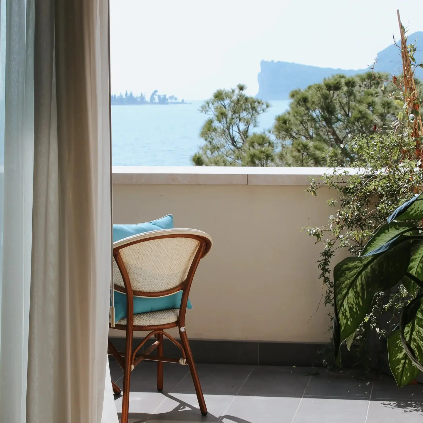 Poltrona con un cuscino azzurro su un balcone con vista sul lago