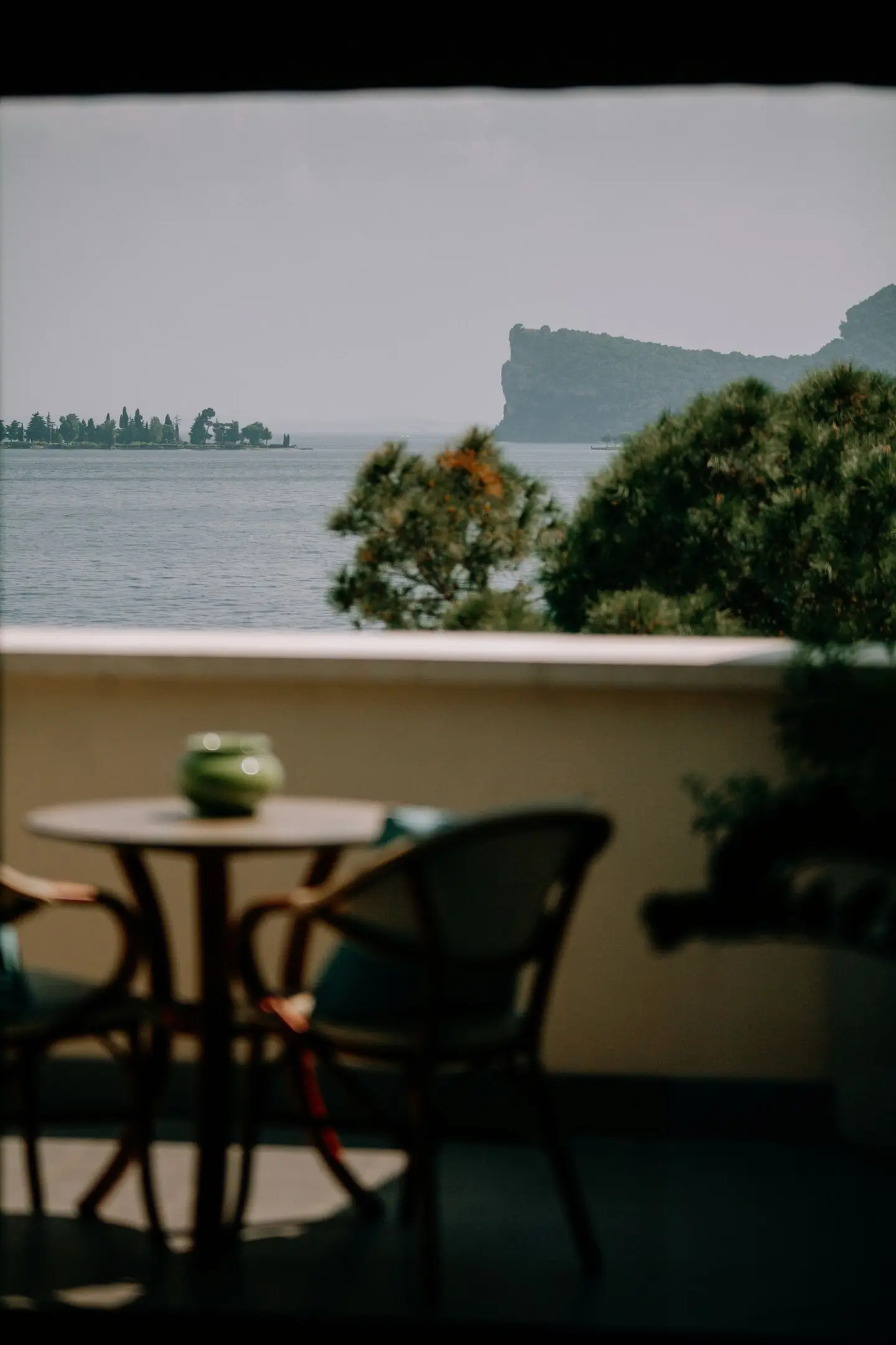 Tavolino e sedie su un balcone con vista sul lago e sulla Rocca di Manerba