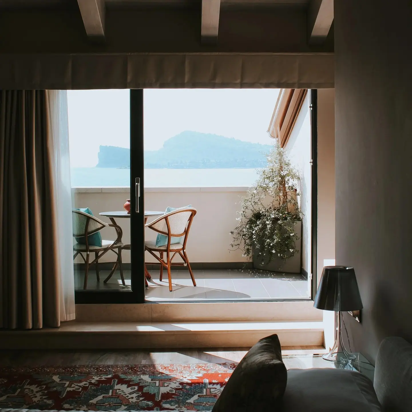 Camera con travi a vista e porta finestra sul balcone, davanti alla Rocca di Manerba