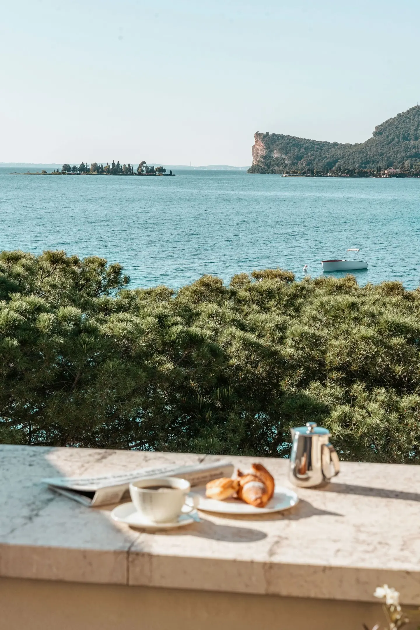 Caffè e cornetti sul parapetto di un balcone, davanti al lago e alla Rocca di Manerba