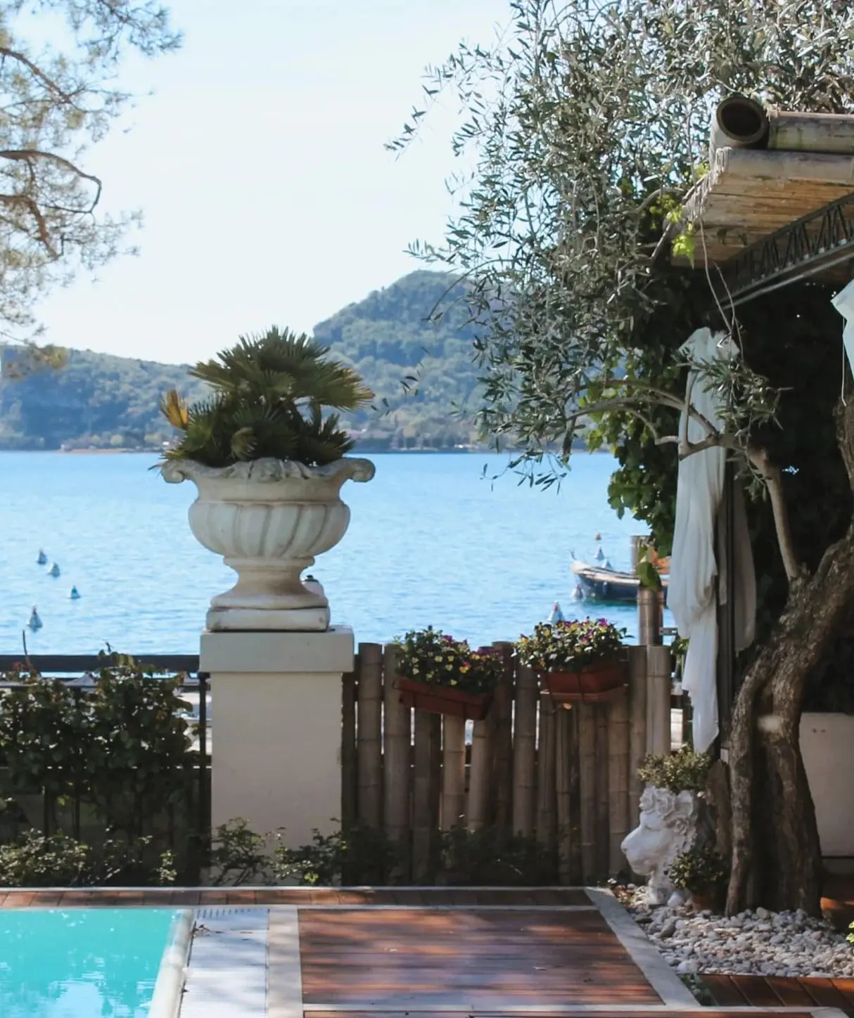 Il giardino con un vaso in pietra, il bordo della piscina e la Rocca di Manerba