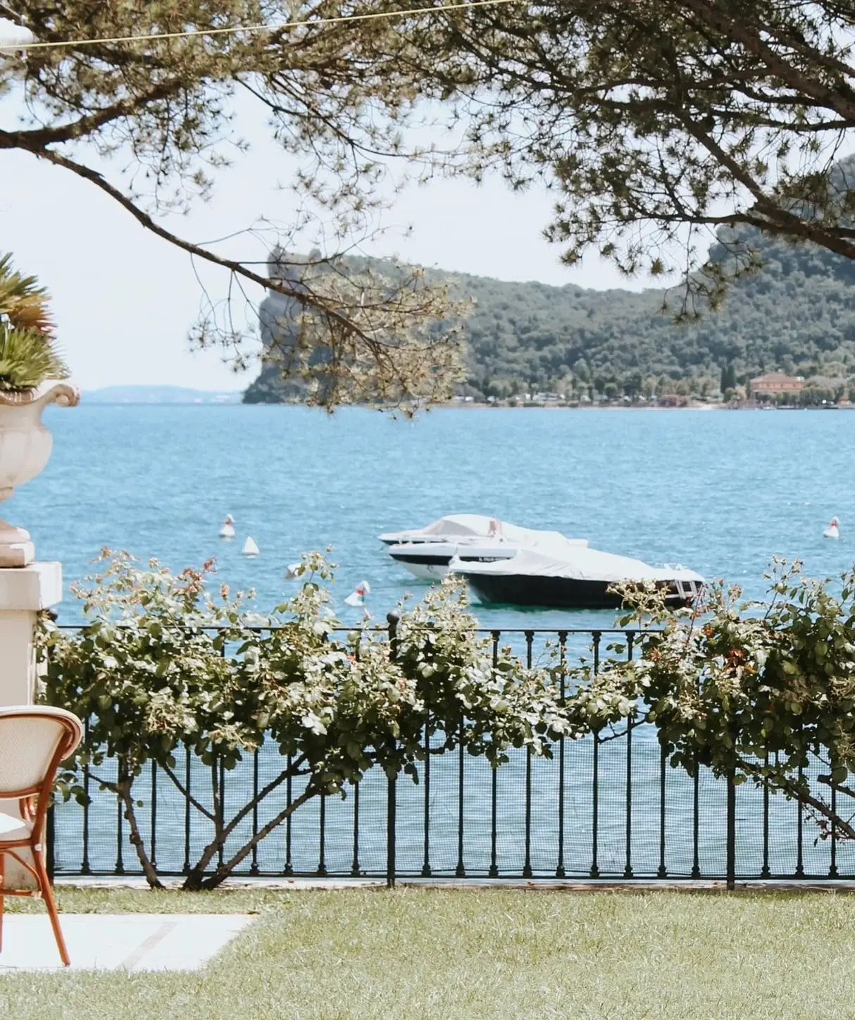 Due motoscafi sul lago davanti al giardino, con la Rocca di Manerba fra i pini