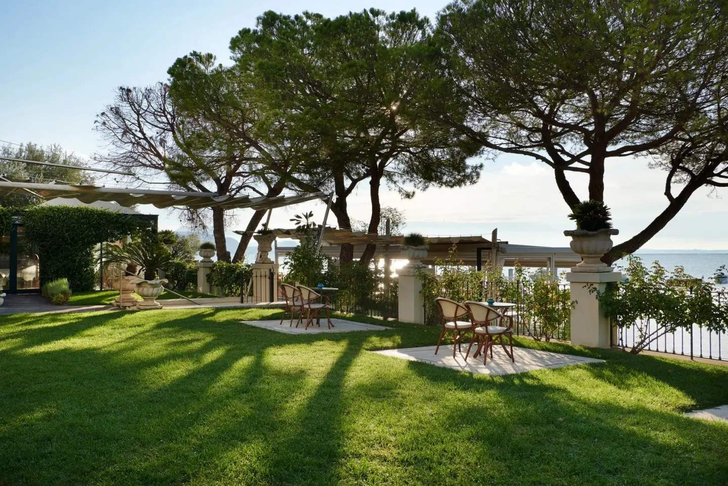 Il prato del giardino all'ombra dei pini, con i tavolini