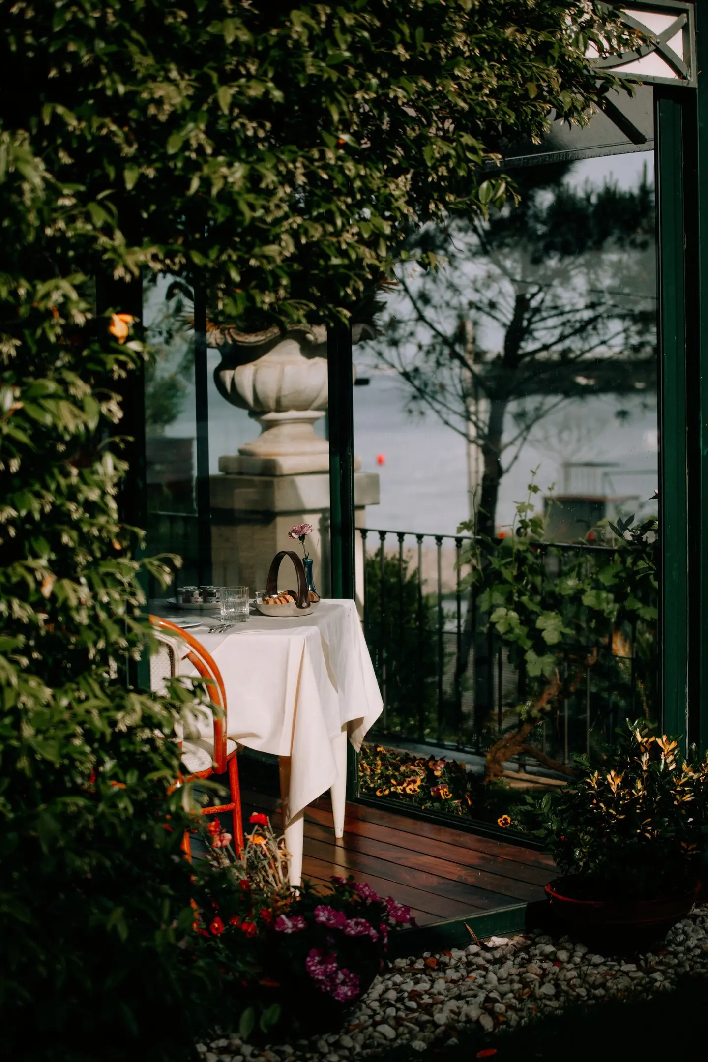 Tavolo apparecchiato nel giardino fra le piante, verso il lago