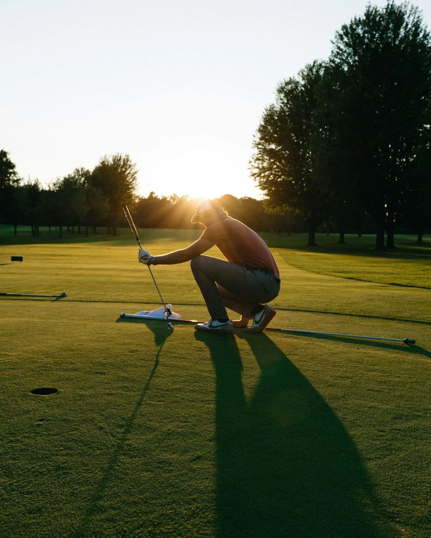 Un golfista sul green al tramonto prepara il colpo