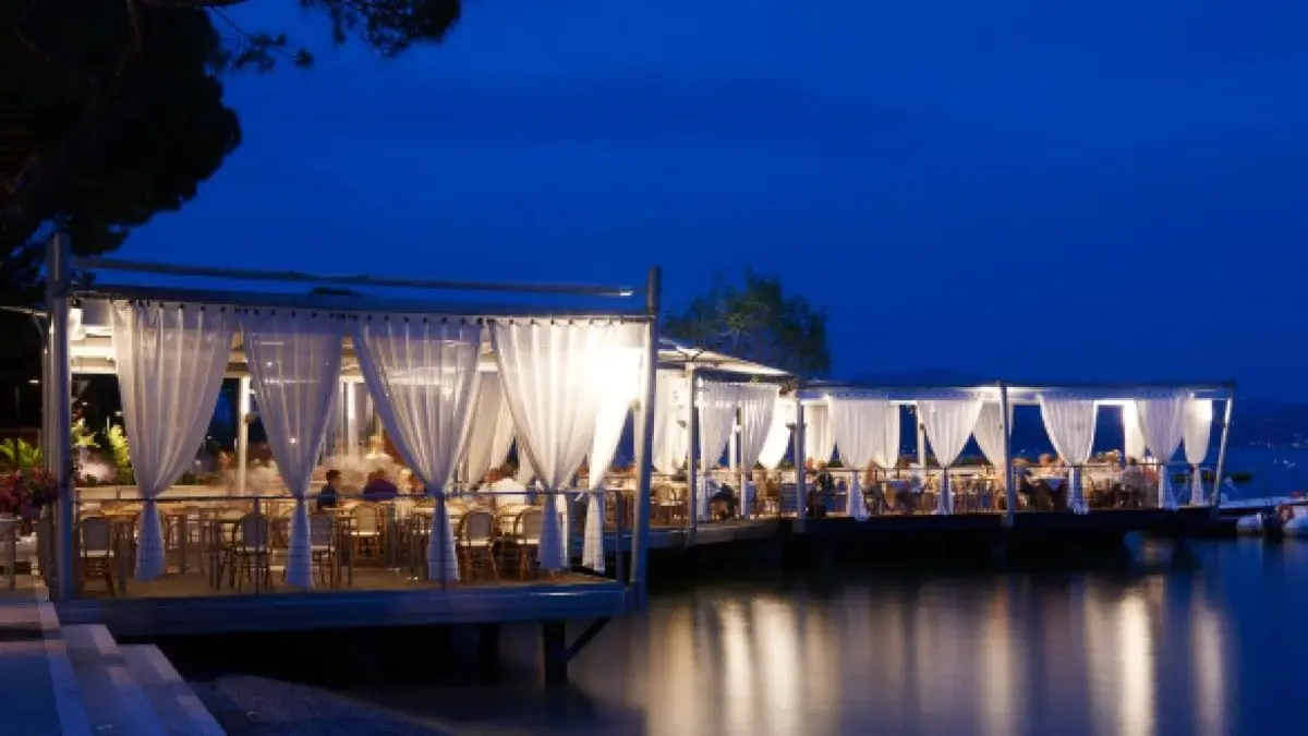 La terrazza del ristorante con le tende, illuminata di sera sul lago