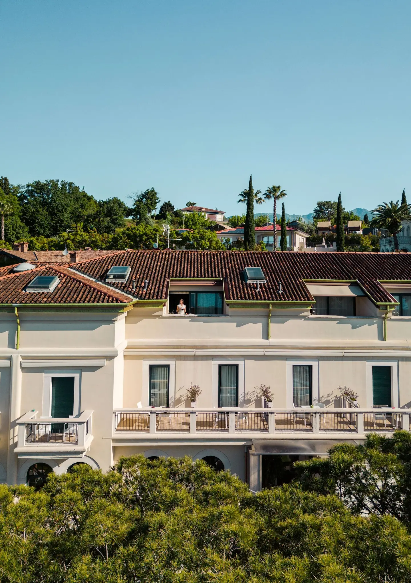 La facciata dell'hotel con i balconi, fra i pini, vista dall'alto