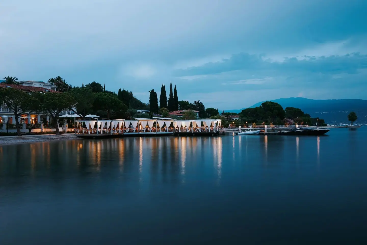 La terrazza del ristorante illuminata all'imbrunire, riflessa nel lago