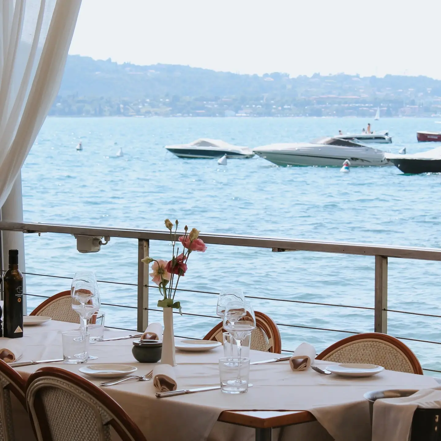 Tavolo apparecchiato sulla terrazza, con i motoscafi sul lago davanti