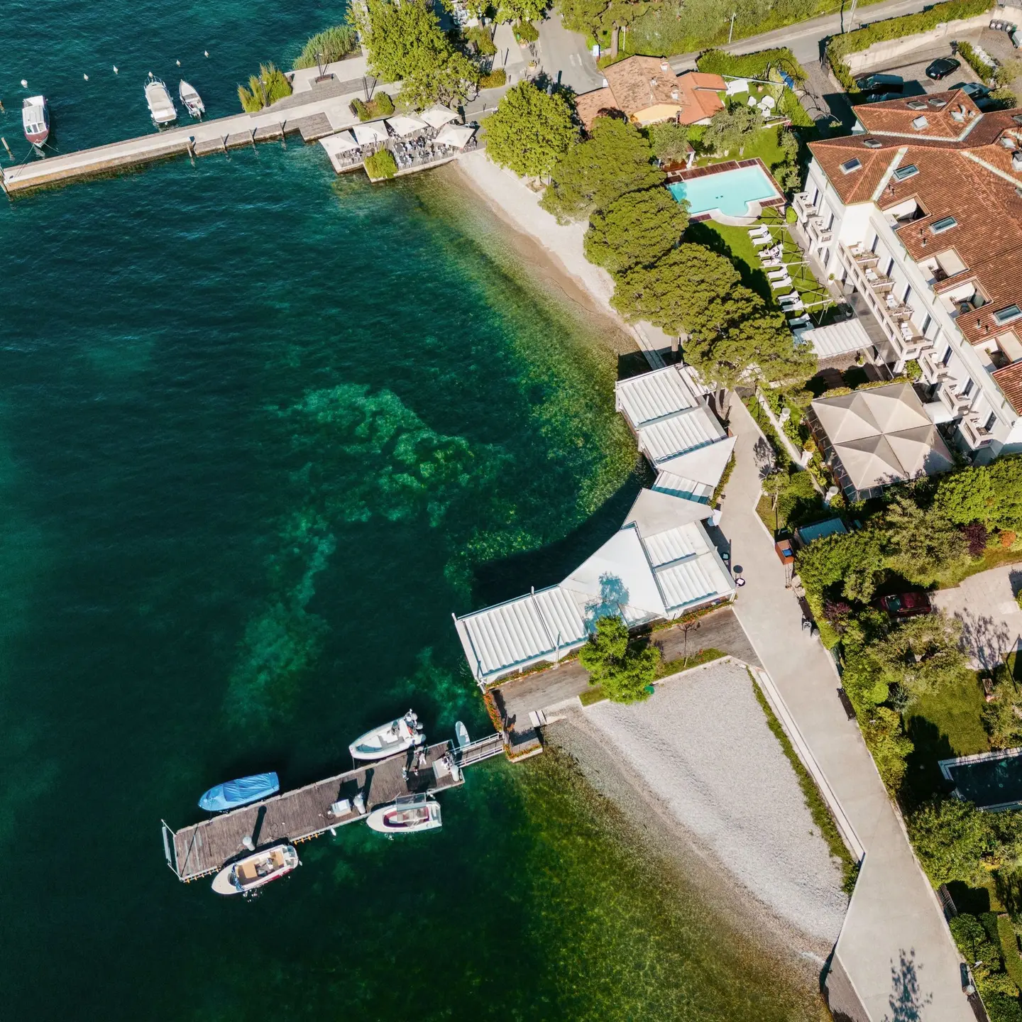 Veduta aerea della riva con il pontile, la terrazza e la piscina dell'hotel