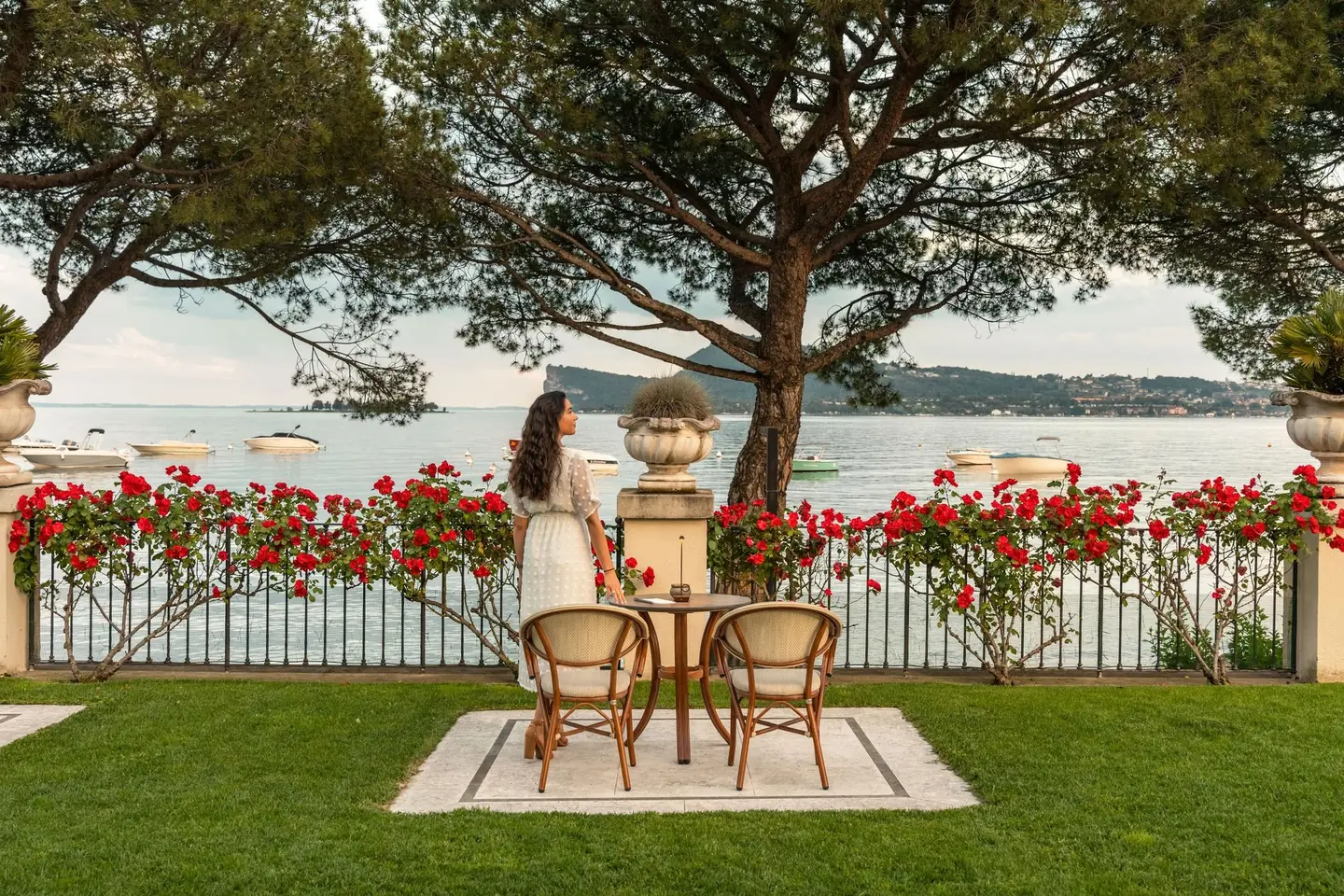 Un'ospite accanto a un tavolino nel giardino, fra le rose, davanti al lago