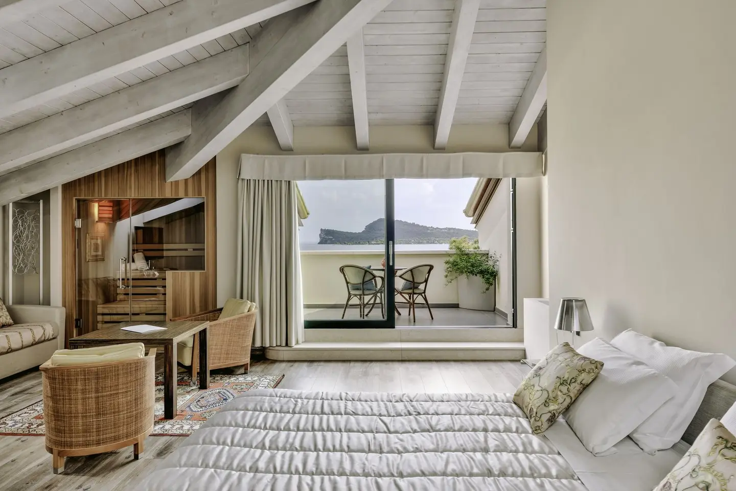 Il letto di una suite davanti al balcone con la vista sulla Rocca di Manerba