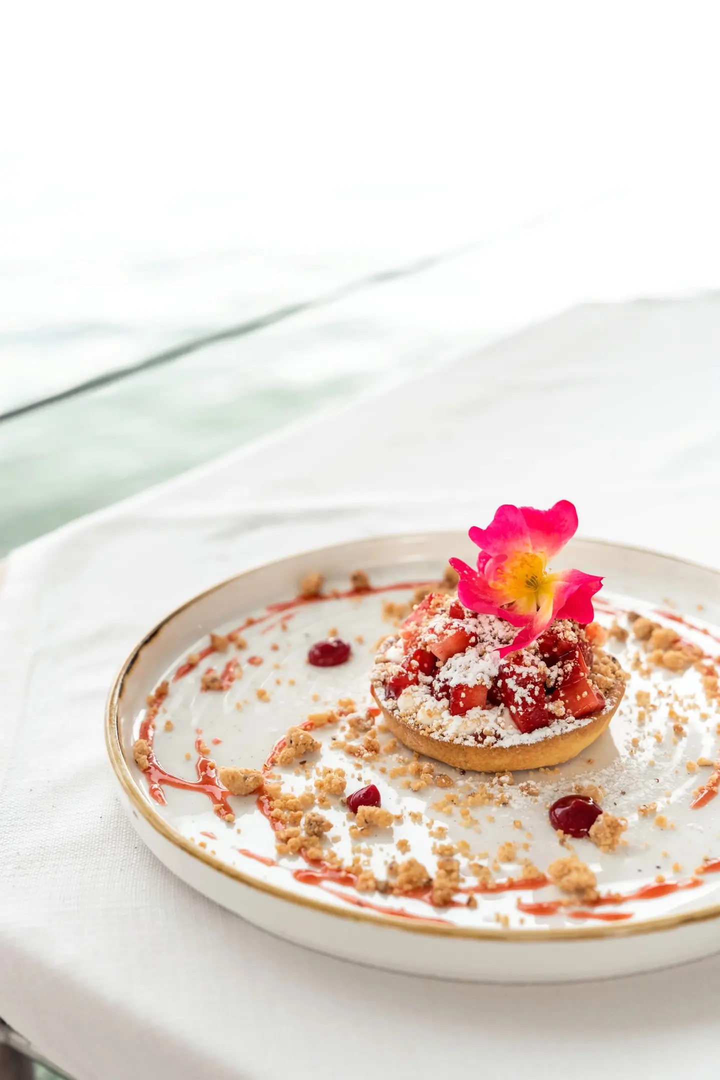Tartelletta con fragole e un fiore su un piatto bianco