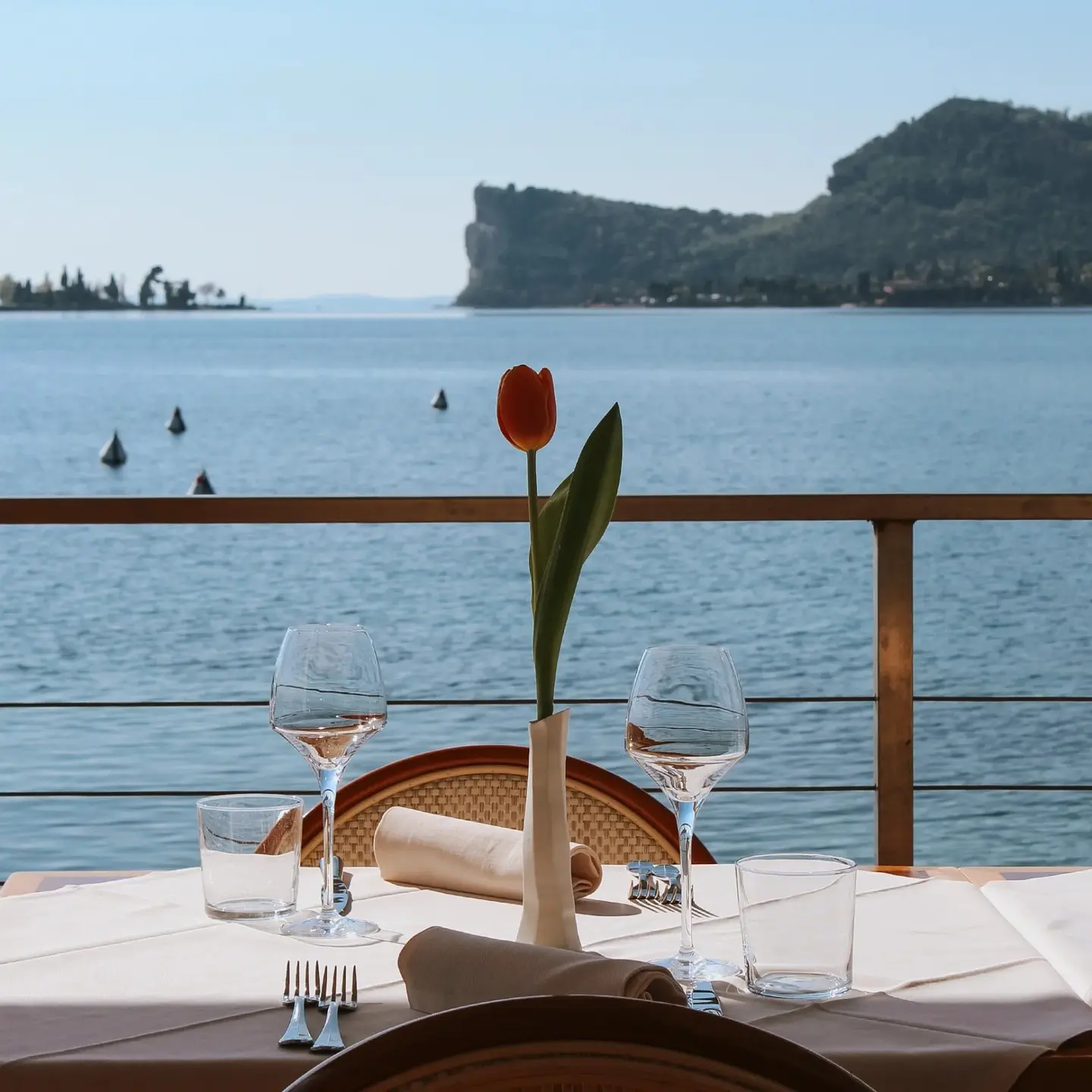 Tavolo con un tulipano sulla terrazza, davanti al lago e alla Rocca di Manerba