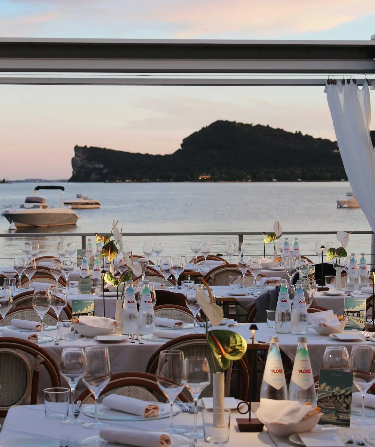 La terrazza del ristorante apparecchiata al tramonto, con la Rocca di Manerba